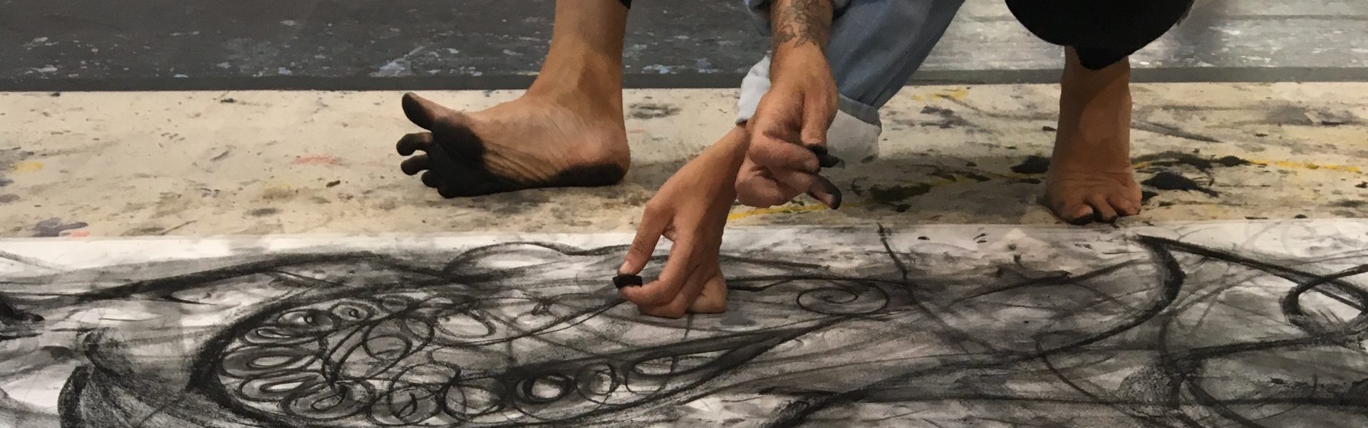 hands and feet of a person working on a large drawing on the floor